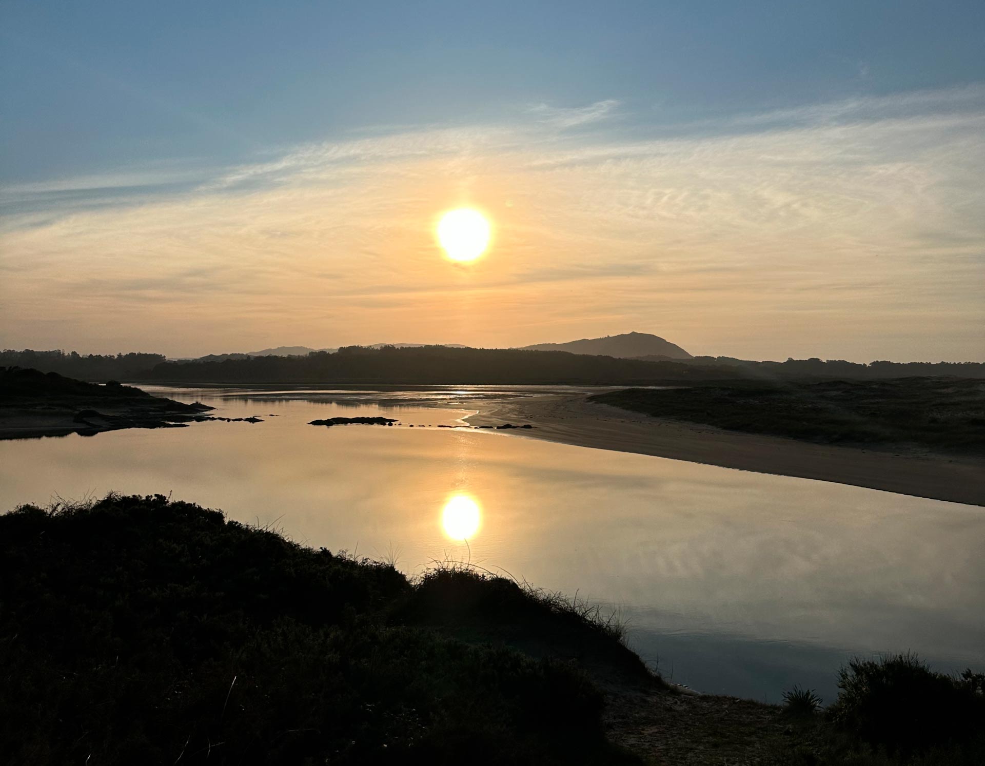 Puesta de sol en la Laguna da Frouxeira en Valdoviño con vista al paisaje natural y el océano Atlántico