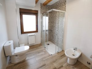 Cuarto de baño de la planta baja de Casa Bieiteiros con mueble de madera, espejo redondo y diseño moderno en Valdoviño