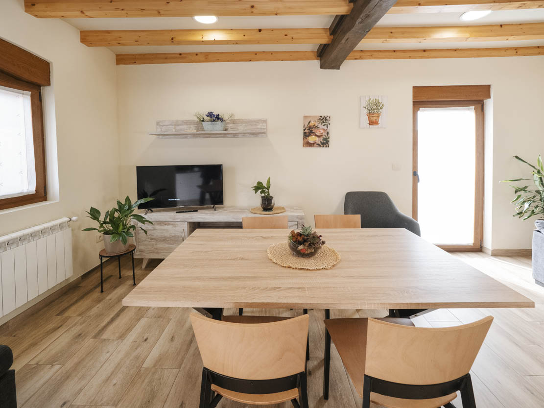 Mesa de comedor de madera clara con sillas de diseño en el salón de Casa Bieiteiros, Valdoviño