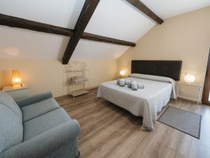 Vista de una habitación con dos camas y un sofá de color oscuro a la izquierda, en la planta alta de Casa Bieiteiros, Valdoviño