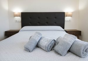 Dormitorio acogedor de Casa Bieiteiros con cama de matrimonio, cabecero oscuro y toallas decorativas para los huéspedes en Valdoviño.