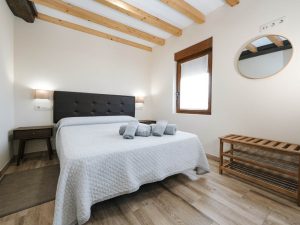 Dormitorio principal de Casa Bieiteiros con cama de matrimonio, toallas de cortesía y techo de vigas de madera en Valdoviño