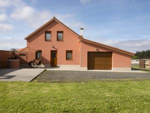 Fachada principal de la casa rural Casa Bieiteiros en Valdoviño, con diseño tradicional de color terracota y entorno verde en Galicia