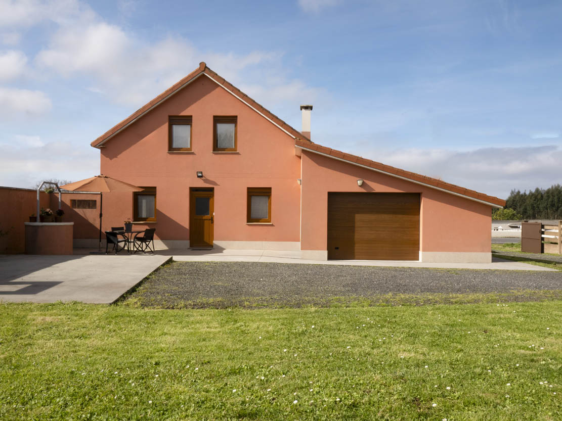 Fachada principal de la casa rural Casa Bieiteiros en Valdoviño, con diseño tradicional de color terracota y entorno verde en Galicia
