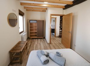 Perspectiva desde la habitación principal de Casa Bieiteiros mostrando el pasillo hacia el baño y las escaleras de acceso, destacando la amplitud y conexión de la planta alta en Valdoviño.