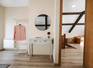 Vista interior de dormitorio con cama de matrimonio a la izquierda, armario abierto y cómoda a la derecha, y puerta al fondo que conecta con la zona de estar para niños en la planta alta de Casa Bieiteiros