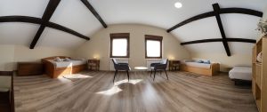 Fotografía panorámica de la planta bajo cubierta en Casa Bieiteiros, destacando las dos grandes claraboyas en el techo de madera y la distribución de camas laterales en Valdoviño