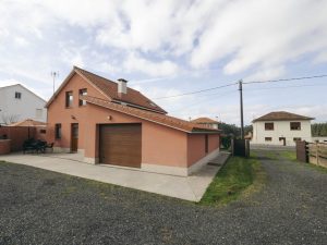 Vista lateral completa de Casa Bieiteiros en Valdoviño, mostrando el acceso desde la carretera, el portalón de entrada y el entorno verde que rodea la propiedad