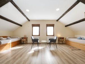 Amplia zona abuhardillada diáfana en Casa Bieiteiros, con techo de madera visto y dos camas individuales a los lados, ideal para niños o adolescentes en Valdoviño